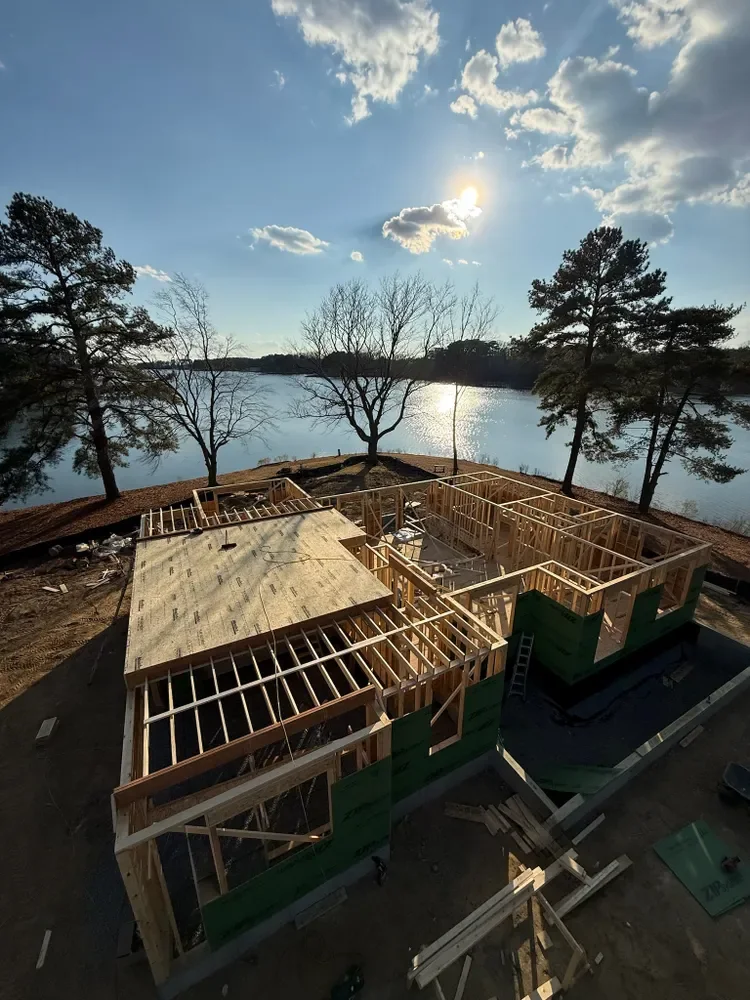 A home being framed beside the water at sunset, seen from above