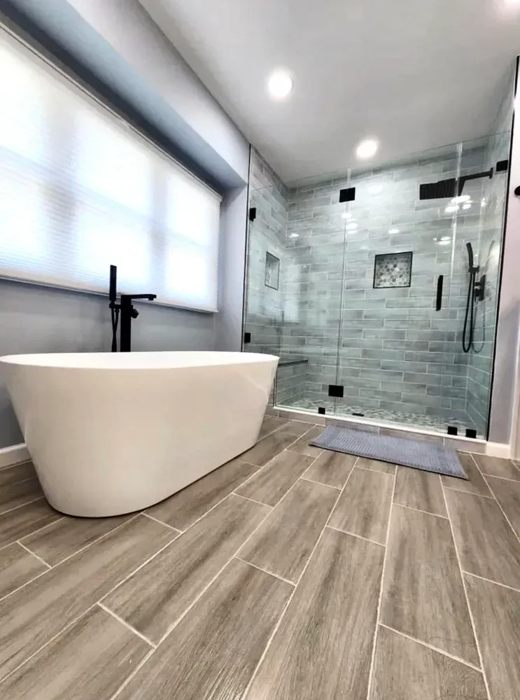 A freestanding tub beside a glass tiled shower