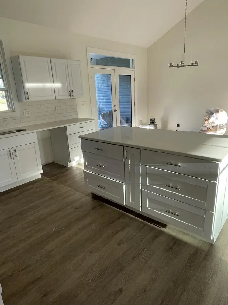 A kitchen island with gray cabinetry and white countertops