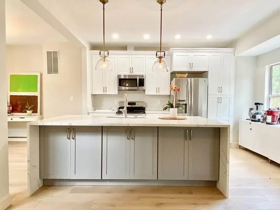 A white kitchen with a large island and glass pendant lights