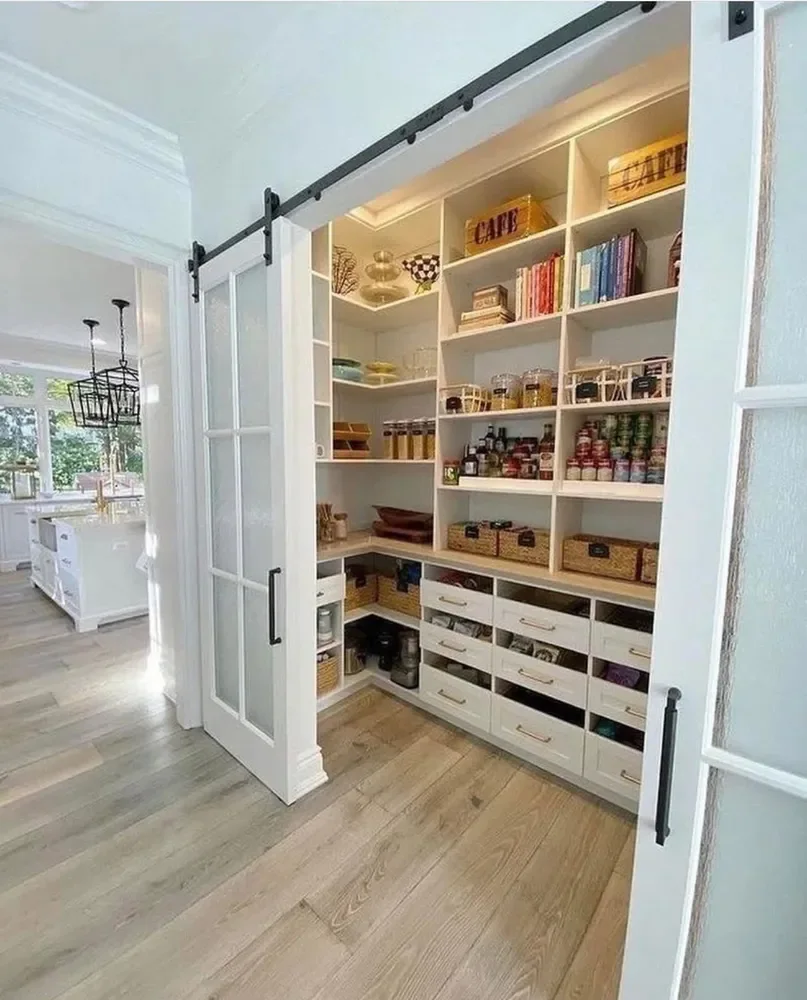 A walk-in pantry with open shelving behind a white barn door