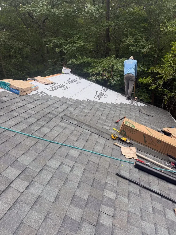 A roofer laying shingles over new underlayment